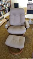 Frontal view of taupe leather swivel recliner chair and ottoman on carpet