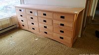 Front view of oak dresser showing all twelve drawers and black metal drop pull handles