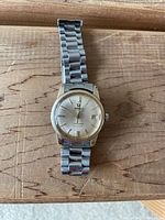 Full view of watch face, bezel and bracelet laid flat on wood surface