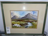 Framed watercolour painting depiction of mountain landscape with river, grassy fields, figure and dog in foreground, signed by Anne Jennings.