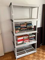 Full view of white plastic shelving unit with books on two middle shelves, top and bottom shelves empty.