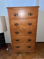 Front view of the tall boy dresser showing five drawers with metal handles in a wood finish.