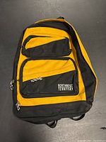 Front view of black and yellow Northwest Territory backpack with multiple zippered compartments.