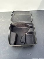Open black hard shell drill case showing custom foam interior compartments shaped to hold drill and components.