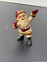 Front view of the ceramic Santa figurine showing facial details and waving arm.