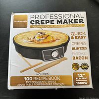 Front view of the boxed basicConcepts Professional Crepe Maker showing features and included items.