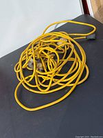 Top-down view of coiled yellow extension cord laid on black surface.