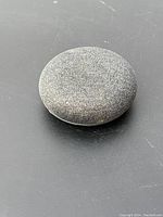 Top view showing fabric covered round smart speaker, dark gray color.