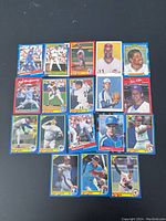 Photo showing 16 baseball cards arranged in a grid, featuring players in various action and posed shots, with diverse colored card borders and team logos visible.