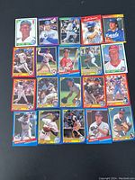 Full view of 20 assorted vintage baseball cards spread on black background showing various players in different teams and poses