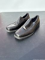 Side angle of men's black slip-on leather dress shoes showing the profile and sole.
