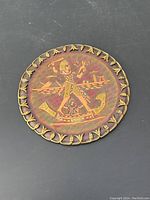 Full view of round plate with embossed Egyptian scene and decorative border