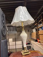 Full side view of the vintage ceramic table lamp with white fabric shade and gold accents on base and neck.