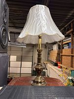 Full view of vintage table lamp with gold ceramic stand and white fabric lampshade.