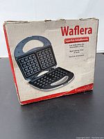 Box showing front and inside view of the waffle maker with product features in Spanish and English