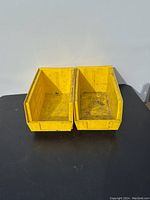 Two individual yellow hook-on storage bins side by side showing open fronts and interior condition with marks.
