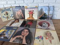 Photo showing all 10 vinyl records laid out in two rows against a brick wall backdrop.