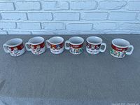 Photo shows all six ceramic Campbell Soup mugs arranged in a single row, highlighting their design and condition.