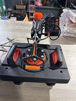 Front view of the heat press machine showing handles, orange adjustment knob, and control panel interface.