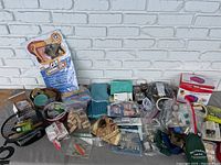 Wide view of the household junk drawer lot showing all items including crafting supplies, tools, batteries, electronic cables, balloon pump, and accessories.