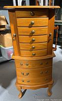 Front view of tall wooden jewelry box with 8 drawers, brass knobs, and curved legs