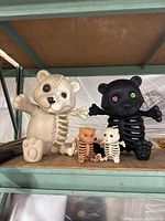 Front view of four Halloween skeleton bears placed on a metal shelf, showing two large bears in the back and two smaller bears in the front.