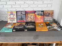 Lot of 10 military strategy board games displayed on a table, showing box fronts and sides.