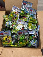 Box filled with multiple sealed packages of yellow coiled insect repellent bracelets with Mickey Mouse charm attached.