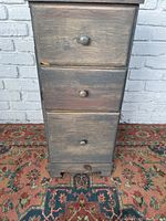 Front view showing three drawers with round wooden knobs, painted and worn finish with visible wear and minor damage.