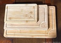 Full view of set of three Goodcups wooden cutting boards stacked largest to smallest showing groove edges and logo.