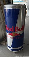 Front view showing the tall cylindrical Red Bull graphic cooler with blue, silver, and red colors.