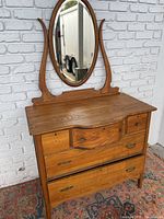 Front view of vintage tiger oak dresser with pivoting oval mirror and five drawers, showing hardware details.
