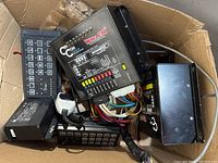 View of Whelen CenCom control units, wired control remotes, wiring harnesses and accessory box inside a cardboard box display.