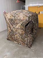 Front and side view of fully assembled camouflage hunting blind with visible mesh windows and support poles.