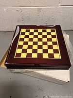 Closed folding wooden game board with a checkered chess board on top.