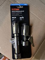 Photo of two chrome cylindrical hitch locks and coupler lock set mounted on black Curt branded card, includes two keys.