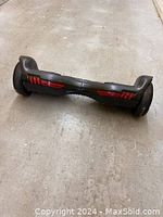 Front angle showing the black hoverboard resting on concrete floor, highlighting red lights and tires.
