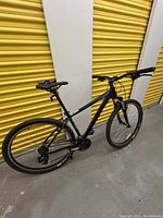 Full side profile view of the Raleigh Talus 1 mountain bike leaning against a storage unit door.