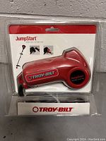 Front view of the Troy-Bilt red JumpStart engine starter in sealed retail blister package, showing product and brand name.