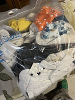 Plastic bag containing multiple cloth diapers in various colors and snap styles, including white, orange, yellow, black, and a fish print diaper.