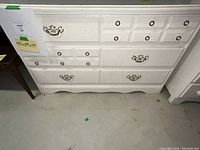 Front view of vintage white wooden dresser showing drawer layout and hardware.