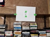 Photo of multiple stacks of vintage cassette tapes arranged on floor beneath a table, showing variety of artists and music genres.