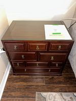 Front view of vintage wooden end table showing nine closed drawers and rectangular top with dark wood finish.