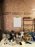 Photo showing an assortment of vintage figurines arranged on a brown surface with reflective plastic in background.