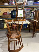 Wooden spindle-back kitchen chairs stacked and arranged to show condition, including wear on seat surface