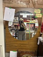 Photo showing the large round mirror set within a teak wood rectangular frame, reflecting the room and person taking the photo. Size indication on frame is 62x32 inches.