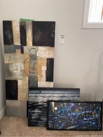 Three abstract artworks shown grouped on carpet leaning against a wall, capturing textures, colors, and relative sizes.