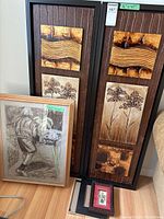 Two large rectangular wood and tree motif wall arts with measurement tags, plus smaller framed drawing and three small framed artworks on floor.