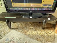 Front view of large solid wood bench with a TV placed on top, showing rounded legs and dark wood finish.
