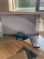 Front view of Bose SoundDock player with silver speaker grille, Bose logo and remote control next to it.